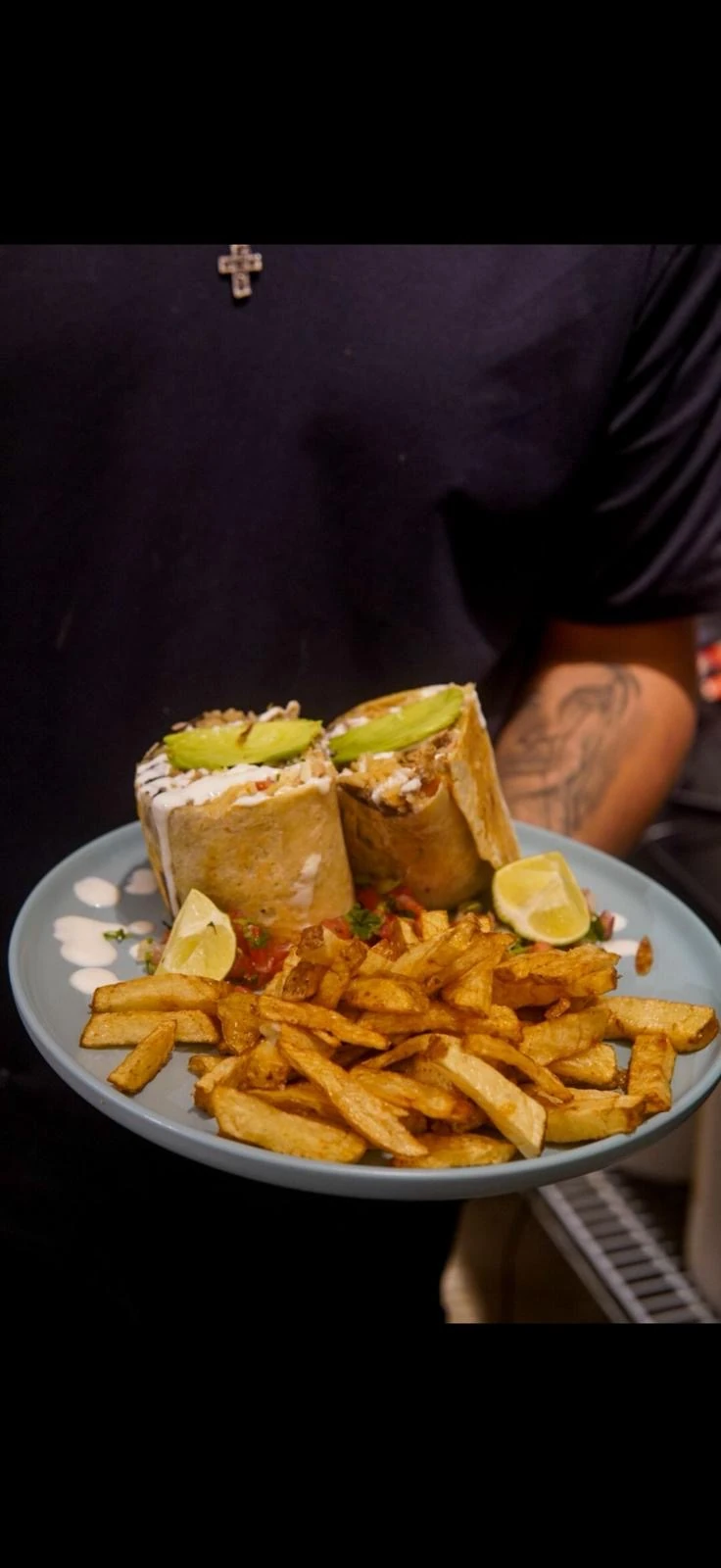 A burrito cut in half with avocado, lime, and fries at Hacienda Santa Teresa