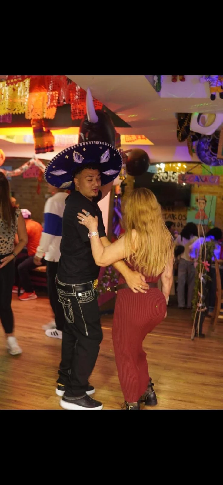 Guests dancing together under colourful lights and Mexican decorations at Hacienda Santa Teresa