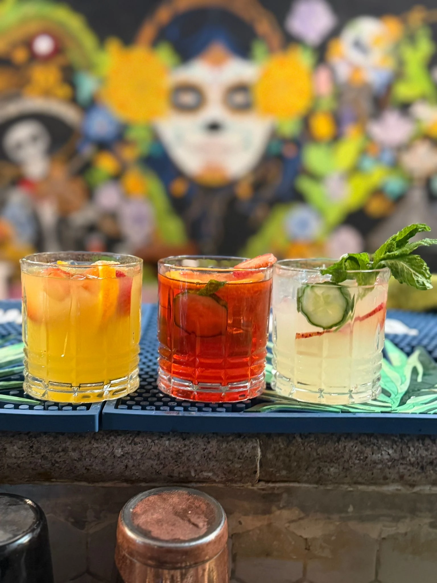 Three colourful Hacienda cocktails with fresh fruit, cucumber, and herb garnishes