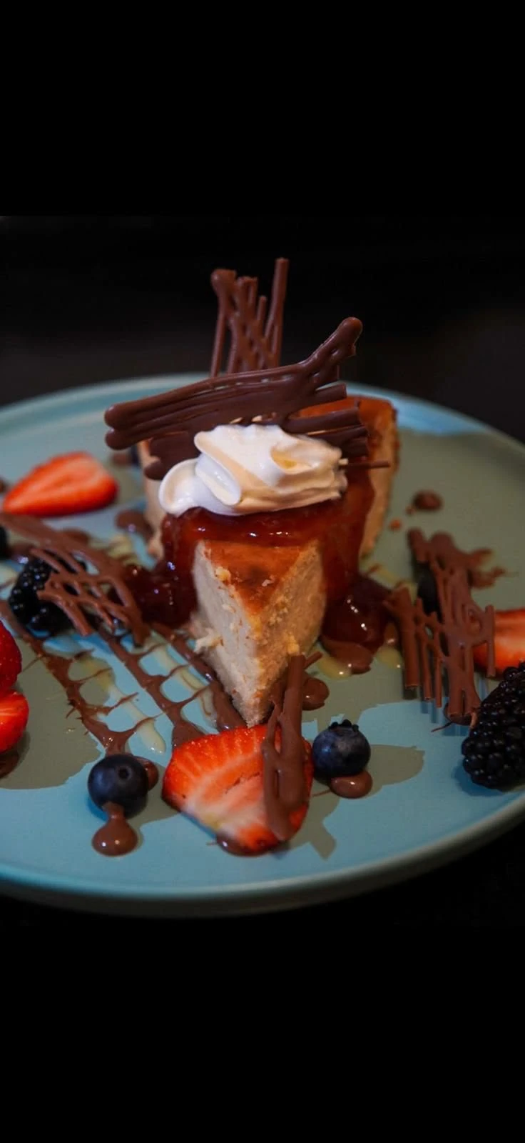 A plated dessert topped with cream and chocolate, served with fresh berries at Hacienda Santa Teresa