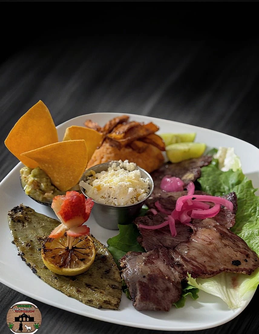 Grilled steak with pickled onions, plantains, guacamole, cheese, and grilled cactus at Hacienda Santa Teresa
