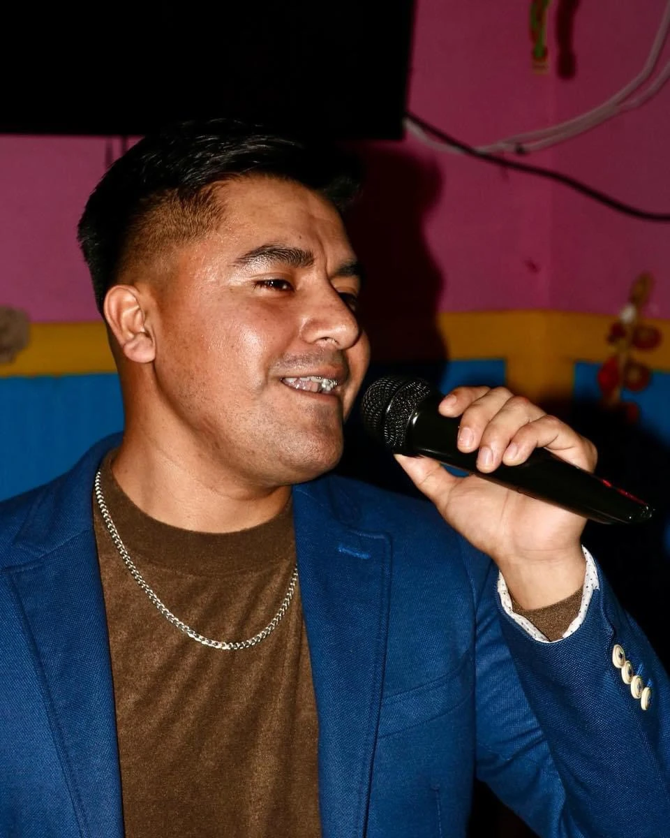 A live singer holding a microphone against Hacienda’s pink and blue restaurant walls