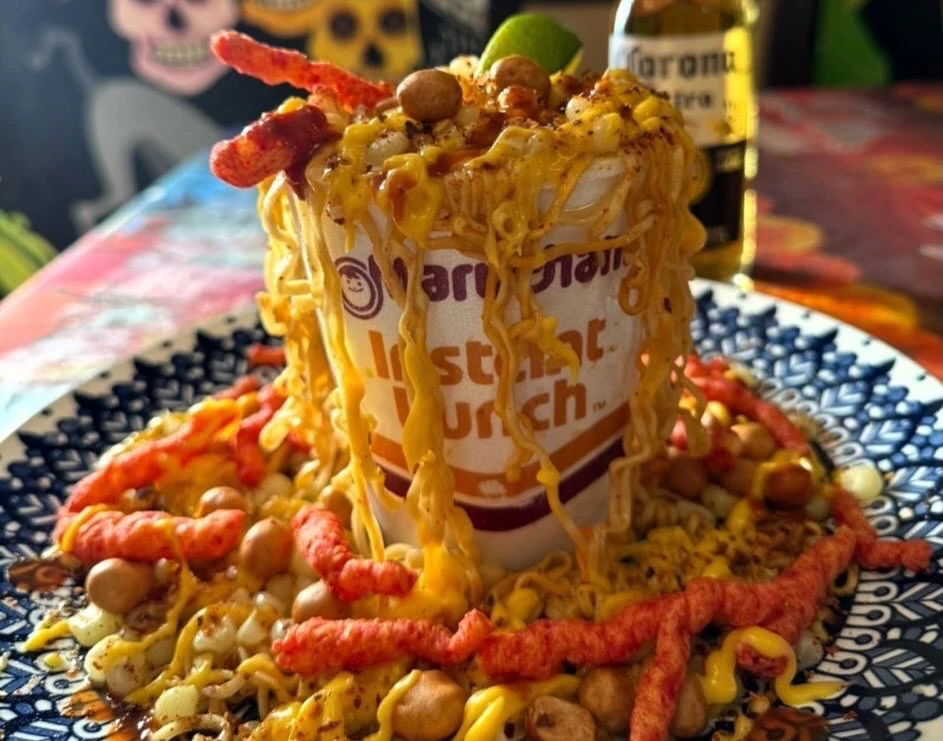 A loaded noodle cup with corn, cheese, crunchy toppings, and lime at Hacienda Santa Teresa