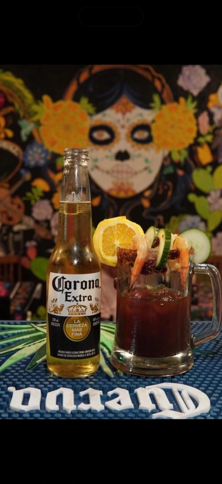 A michelada garnished with shrimp, cucumber, and citrus beside a beer at Hacienda Santa Teresa