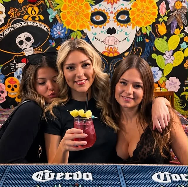 Guests enjoying a colourful cocktail in front of Hacienda’s Mexican artwork