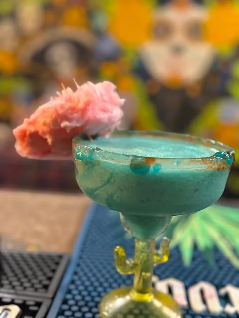 A blue cocktail with a cotton candy garnish on the bar at Hacienda Santa Teresa